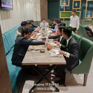 a group of people sitting at a table eating at Hotel The Coal in Alīgarh