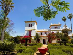 a large white building with palm trees and a garden at Hacienda Don Rodrigo in Alcalá de Guadaira