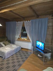 a bedroom with a bed and a tv and curtains at Przytulisko Dom na wyłączność in Biały Dunajec