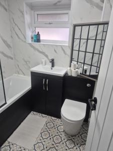 a bathroom with a sink and a toilet and a tub at James' Place @1 Gwynnes in Merthyr Tydfil