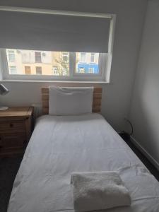 a bedroom with a white bed with a window at James' Place @1 Gwynnes in Merthyr Tydfil