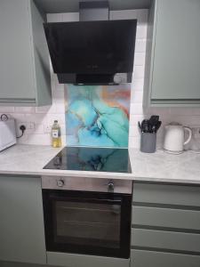 a kitchen counter with a stove and a microwave at James' Place @1 Gwynnes in Merthyr Tydfil