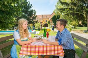 un hombre y una mujer sentados en una mesa de picnic en Winzerhof Familie Bogner, en Rohrendorf bei Krems