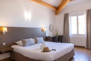 a bedroom with a large bed with a hat on it at Hôtel Les Lentisques in Cargèse