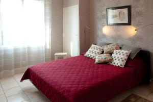 Un dormitorio con una cama roja con almohadas. en Appartement d artiste en Hyères