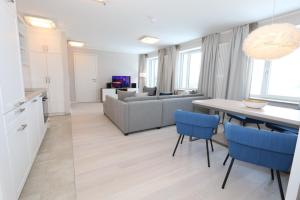 a kitchen and living room with a table and blue chairs at Prora Block 1 - Sauna, Pool und Fitness - Meerzeit in Binz