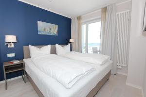 a bedroom with a large white bed with a blue wall at Prora Block 1 - Sauna, Pool und Fitness - Meerzeit in Binz