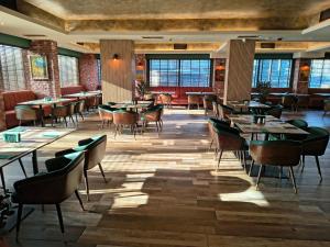 a dining room with tables and chairs and windows at Hotel Golden Tulip Varna in Varna City +96 photos