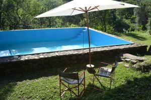 two chairs and an umbrella next to a swimming pool at Finca La Colorada in San Salvador de Jujuy +25 photos