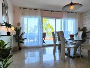 a dining room with a table and chairs and a view at Home Ocean 360 piscine chauffée et SPA in Saint-Leu