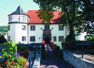 a large white building with a red roof at C&S Living I Wohnung I Balkon I Küche I Stellplatz in Hardheim