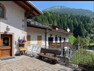 a house with a bench on a balcony with a mountain at Dolomiti Cadore Home in San Pietro di Cadore