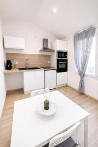 a white kitchen with a white table and chairs at Le cocon - STUDIO- MACON in Saint-Laurent-sur-Saône +3 photos