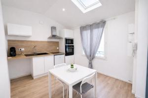 a white kitchen with a white table and a window at Le cocon - STUDIO- MACON in Saint-Laurent-sur-Saône