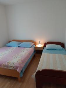 a bedroom with two beds and a table with a lamp at Apartments Dubrovnik Two in Povljana