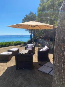 a table and chairs under an umbrella on the beach at Fetovaia Magic Holiday Villa in Fetovaia