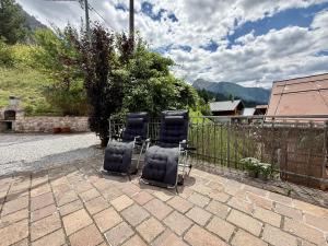 three chairs sitting on a patio in front of a fence at Dolomiti Cadore Home in San Pietro di Cadore