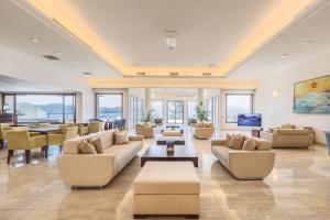 a large living room with couches and tables and windows at Porto Galini Seaside Resort & Spa in Nikiana