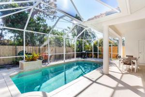 an indoor swimming pool with a pergola and a house at Imola Vacation Rental - Remodeled Pool Home Minutes from Vanderbilt Beach! Family-Friendly Retreat with 4 BR 4 BA and Private Screened Pool! in Naples