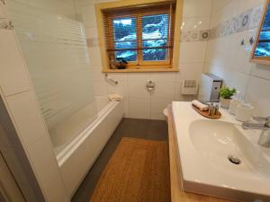 a white bathroom with a sink and a shower at B&B Le Chalet in Les Sciernes d'Albeuve