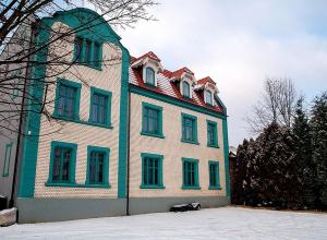 a large building with green windows on a snow covered yard at Willa na Dębowej in Katowice