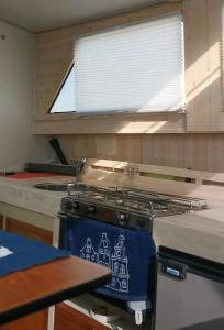 a kitchen with a stove with a sink and a window at Sleeping on the GilgaBoat! in Nakskov