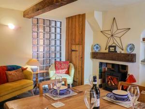 a living room with a table and a fireplace at Rope Cottage in Bridport