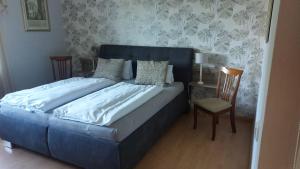 a blue bed in a bedroom with a chair at Apartmán Rainbow se zahradou, bazénem a parkováním in Karlovy Vary