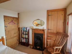 a bedroom with a fireplace and a chair and a mirror at Rope Cottage in Bridport