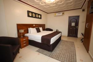 a bedroom with a bed and a chair and a couch at Airport West Hotel in Accra