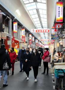 people wearing face masks walk through a food market at Kobe Youth Hostel in Kobe