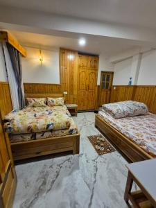 two beds in a bedroom with wooden walls and wooden cabinets at Pranavan Homestay in Mirik +20 photos