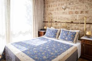 a bedroom with a bed with a blue blanket and pillows at Hagiati Guesthouse - Edessa Cozy Mountain Retreat in Edessa