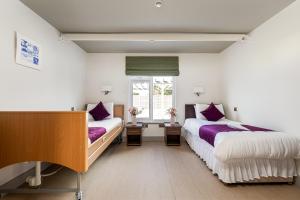 a bedroom with two beds and a window at Maison des Landes - Accessible Hotel in St. Ouen's