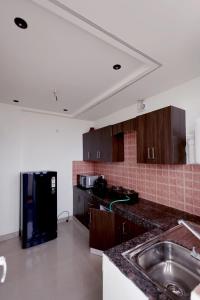 a kitchen with a sink and a black refrigerator at Supremo Home Stays in Agra