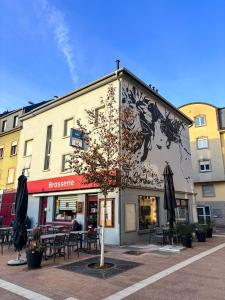 a building with tables and umbrellas in front of it at Apartment Café Ettelbrück in Ettelbruck