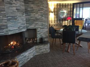 a living room with a fireplace and a table and chairs at Hôtel Panorama in Munster