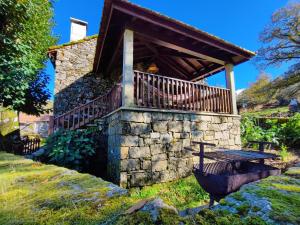 a stone house with a wooden balcony and a table at Casa do Rio, Natureza - Nova Gestão in Melgaço