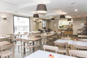 a restaurant with white tables and white chairs at Terres de France - Appart'Hotel Quimper Bretagne in Quimper