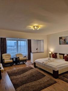a bedroom with a bed and two chairs and a table at Pensiunea Denim in Şelimbăr