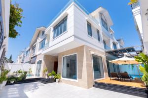 a white house with a patio and an umbrella at B2-11 Hoàng My Villa in Vung Tau