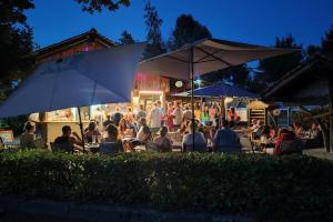 a group of people sitting at tables under umbrellas at Camping le Relais du Léman in Messery +97 photos