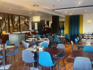 a restaurant with wooden tables and blue chairs at Kyriad Dijon Est Mirande in Dijon +49 photos