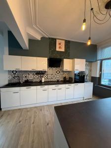 a kitchen with white cabinets and a black counter top at Duplex dans le centre d'Heusy in Verviers