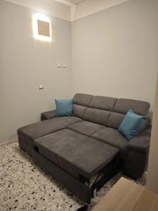 a brown couch in a living room with blue pillows at Arlecchino Rooms in Santa Maria Codifiume