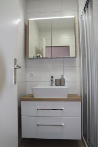 a bathroom with a white sink and a mirror at Ferienwohnungen Neubauer in Kaltenberg +27 photos