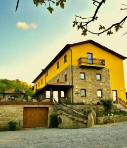a large yellow building with a garage in front of it at Quinta do Limite - Country House in Covilhã
