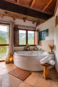 a large bath tub in a bathroom with windows at Carbayu Senda del Oso in Proaza