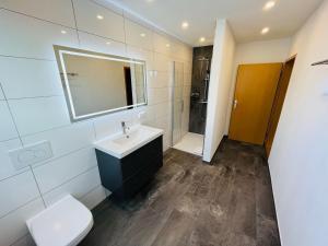 a bathroom with a sink and a toilet and a mirror at Ferienwohnung am Eberbach in Stadtoldendorf +16 photos