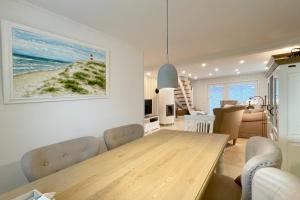 a living room with a dining room table and a living room with a beach at Ferienhaus Eibenweg 6 in Tinnum +18 photos
